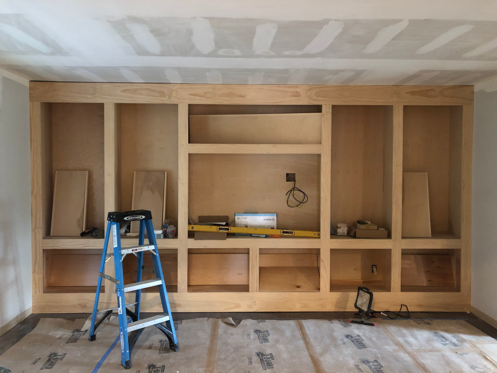 Basement renovation in progress with custom built-in wood framing and shelving installation