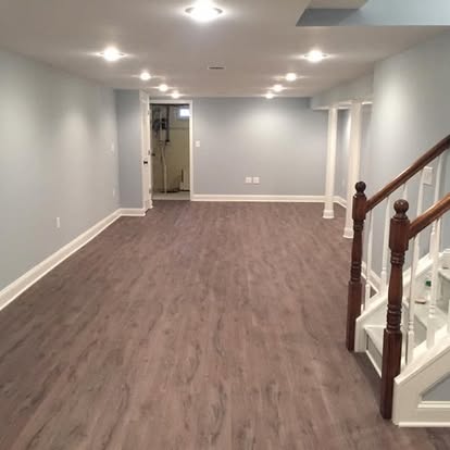 Finished basement remodel with modern flooring, recessed lighting, and open layout design