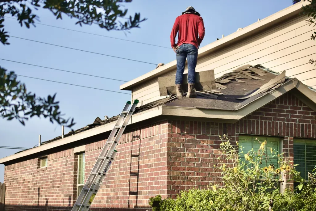 Roofing worker standing beside exposed shingles on a residential roof